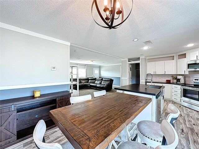 8851 C 469, Center Hill, FL 33514 - kitchen with appliances with stainless steel finishes, dark countertops, light wood finished floors, white cabinets, and a kitchen island with sink