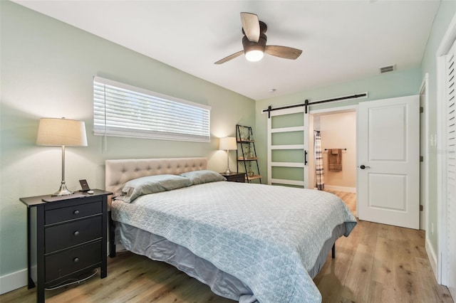 1529 Essex Dr N, Saint Petersburg, FL 33710 - bedroom with a barn door, light wood-type flooring, baseboards, and ensuite bath