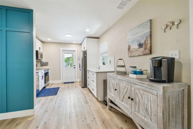 1529 Essex Dr N, Saint Petersburg, FL 33710 - kitchen with stainless steel appliances, light wood-style floors, white cabinets, recessed lighting, and baseboards