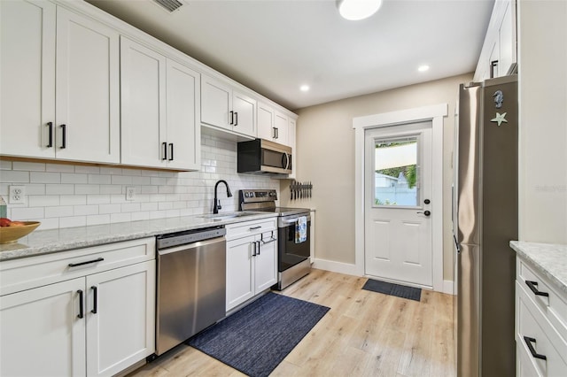 1529 Essex Dr N, Saint Petersburg, FL 33710 - kitchen with stainless steel appliances, a sink, tasteful backsplash, light wood-style flooring, and baseboards