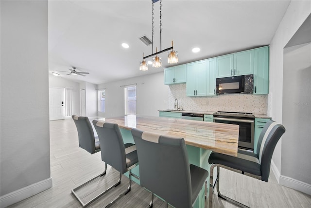 11363 Cocoa Beach Dr, Riverview, FL 33569 - kitchen with appliances with stainless steel finishes, baseboards, tasteful backsplash, a sink, and blue cabinets