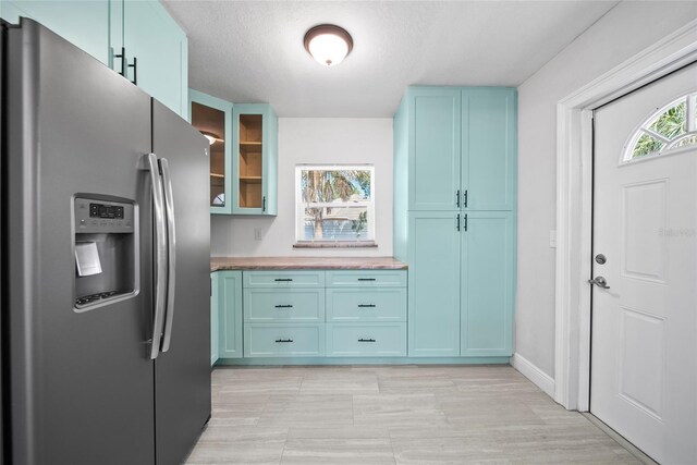 11363 Cocoa Beach Dr, Riverview, FL 33569 - kitchen with stainless steel refrigerator with ice dispenser, blue cabinets, glass insert cabinets, baseboards, and light countertops