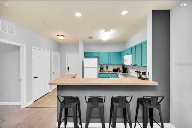 3175 Feltrim Pl Unit 405, Kissimmee, FL 34747 - kitchen with white appliances, blue cabinetry, a peninsula, a kitchen breakfast bar, and recessed lighting