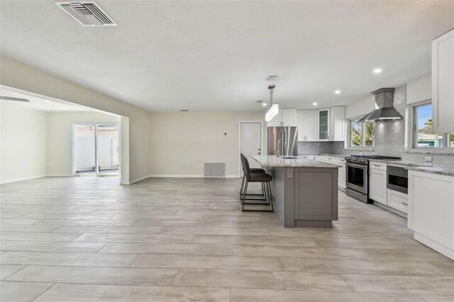 94 Nicholas Dr, Dunedin, FL 34698 - kitchen featuring appliances with stainless steel finishes, wall chimney exhaust hood, open floor plan, a kitchen island, and light wood finished floors