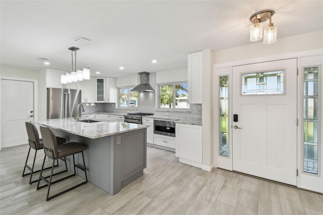 94 Nicholas Dr, Dunedin, FL 34698 - kitchen featuring high quality appliances, wall chimney range hood, white cabinetry, an island with sink, and a sink