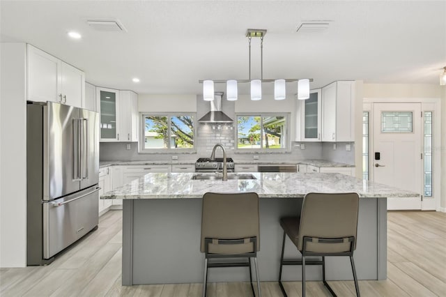 94 Nicholas Dr, Dunedin, FL 34698 - kitchen featuring high end fridge, a sink, wall chimney exhaust hood, backsplash, and white cabinetry