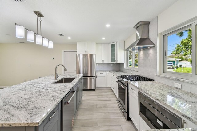 94 Nicholas Dr, Dunedin, FL 34698 - kitchen with stainless steel appliances, a sink, wall chimney range hood, light stone countertops, and tasteful backsplash