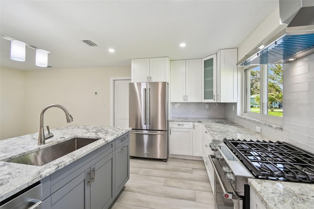 94 Nicholas Dr, Dunedin, FL 34698 - kitchen with stainless steel appliances, a sink, wall chimney range hood, backsplash, and light stone countertops