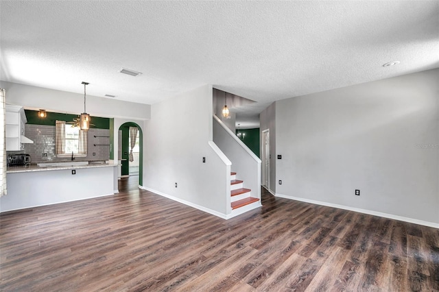 1204 Rinkfield Pl, Brandon, FL 33511 - unfurnished living room featuring dark wood finished floors, a textured ceiling, stairs, and arched walkways