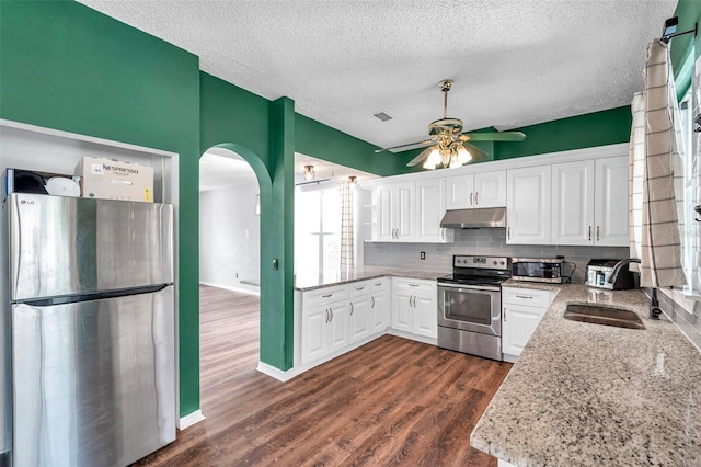 1204 Rinkfield Pl, Brandon, FL 33511 - kitchen featuring appliances with stainless steel finishes, under cabinet range hood, a ceiling fan, arched walkways, and a textured ceiling