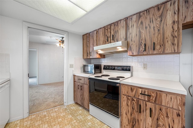 1211 Stony Brook Ln, Dunedin, FL 34698 - kitchen with range with electric stovetop, under cabinet range hood, black microwave, light countertops, and brown cabinets
