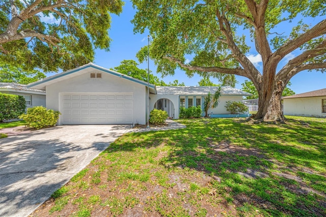 1211 Stony Brook Ln, Dunedin, FL 34698 - ranch-style home with an attached garage, stucco siding, concrete driveway, and a front lawn