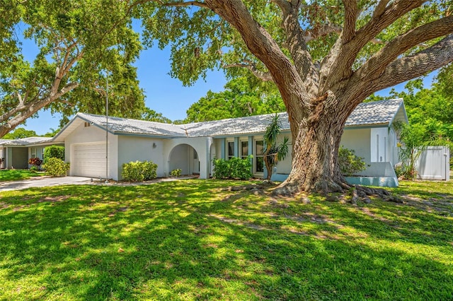 1211 Stony Brook Ln, Dunedin, FL 34698 - ranch-style house with an attached garage, stucco siding, concrete driveway, and a front yard