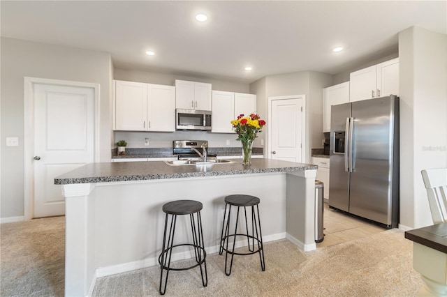 6180 Spring Crayfish Ave, New Port Richey, FL 34653 - kitchen featuring appliances with stainless steel finishes, a sink, dark countertops, a breakfast bar, and white cabinetry
