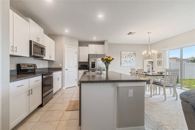 6180 Spring Crayfish Ave, New Port Richey, FL 34653 - kitchen with stainless steel appliances, a sink, dark countertops, white cabinetry, and an island with sink