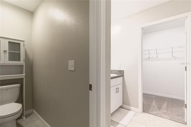 6180 Spring Crayfish Ave, New Port Richey, FL 34653 - bathroom with vanity, toilet, a spacious closet, baseboards, and tile patterned flooring