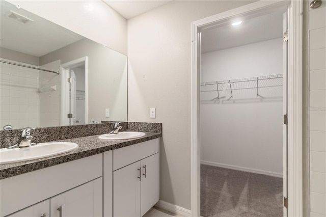 6180 Spring Crayfish Ave, New Port Richey, FL 34653 - bathroom with double vanity, a walk in closet, a tile shower, and baseboards