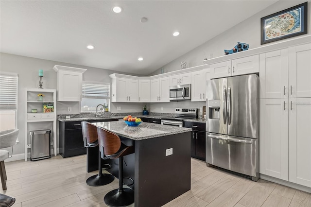 6741 51st Way N, Pinellas Park, FL 33781 - kitchen with stainless steel appliances, vaulted ceiling, a kitchen island, white cabinets, and light stone countertops
