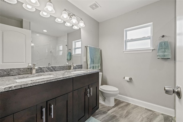 6741 51st Way N, Pinellas Park, FL 33781 - bathroom with a marble finish shower, toilet, baseboards, double vanity, and plenty of natural light