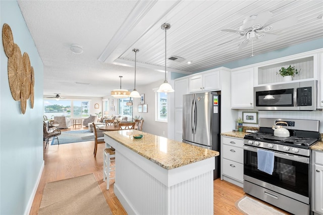 6075 Shore Blvd S Unit 215, Gulfport, FL 33707 - kitchen with appliances with stainless steel finishes, a ceiling fan, light wood finished floors, a kitchen island, and open floor plan