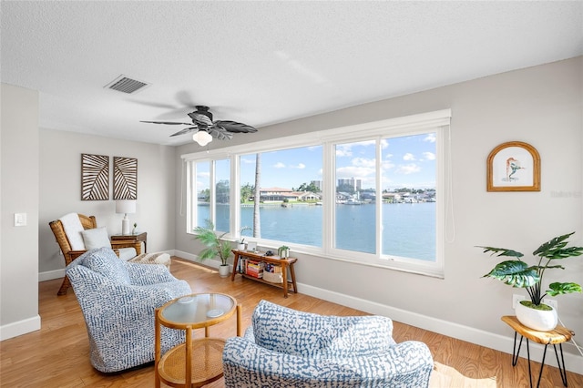 6075 Shore Blvd S Unit 215, Gulfport, FL 33707 - living area featuring plenty of natural light, baseboards, a ceiling fan, light wood finished floors, and a textured ceiling