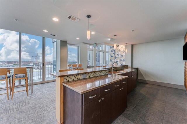 777 N Ashley Dr Unit 1506, Tampa, FL 33602 - kitchen with a sink, dark brown cabinets, pendant lighting, a large island, and light stone counters