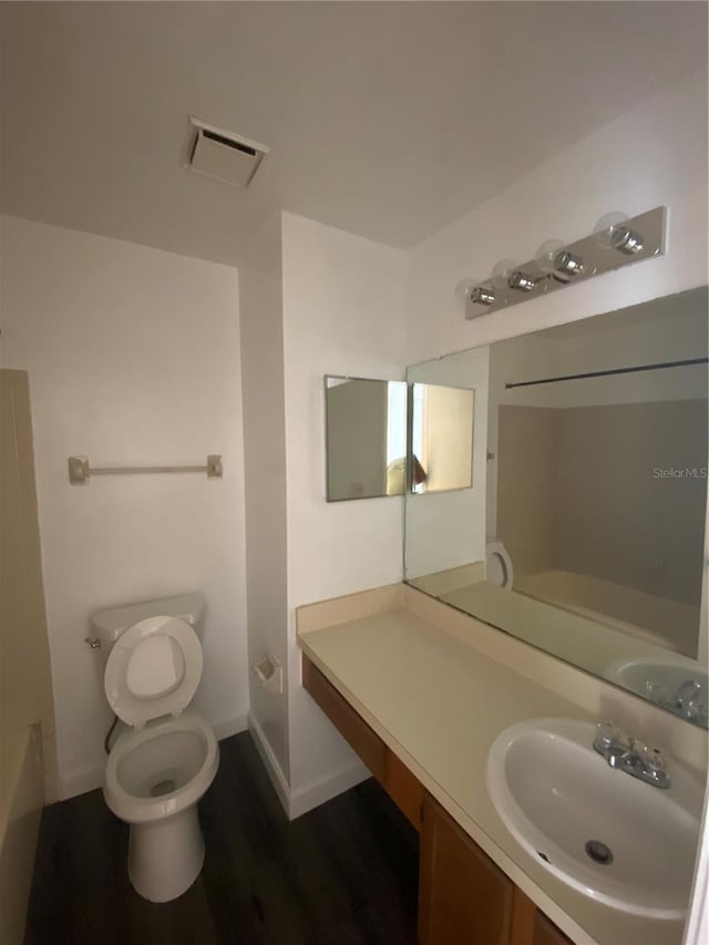 8708 Cobbler Pl, Tampa, FL 33615 - bathroom with toilet, vanity, a bathtub, wood finished floors, and baseboards