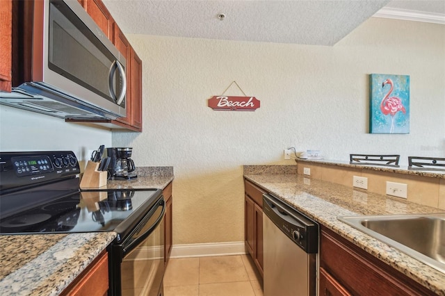 10315 Gulf Blvd Unit 302, Saint Petersburg, FL 33706 - kitchen featuring stainless steel appliances, a textured wall, a textured ceiling, baseboards, and light tile patterned floors