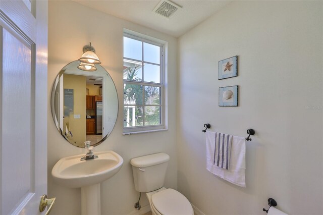 half bath featuring toilet and baseboards
