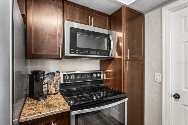 6137 Halifax Dr, New Port Richey, FL 34653 - kitchen with appliances with stainless steel finishes, dark brown cabinets, light stone countertops, and a textured wall