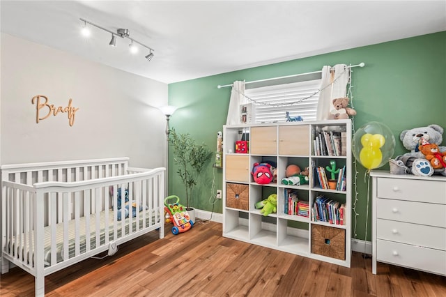 6137 Halifax Dr, New Port Richey, FL 34653 - bedroom featuring a nursery area, wood finished floors, rail lighting, and baseboards