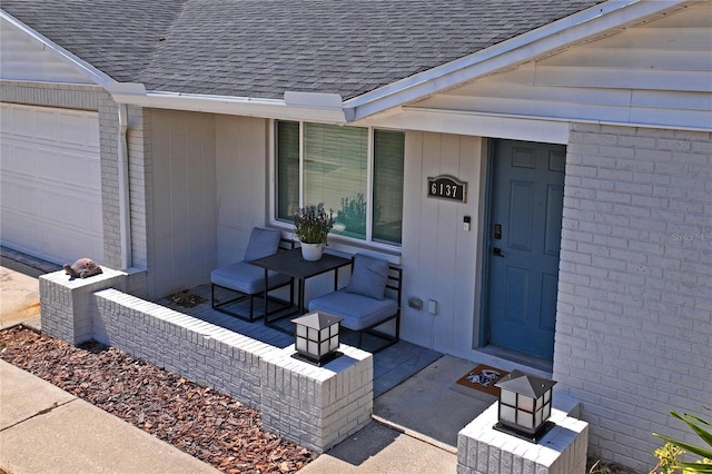 6137 Halifax Dr, New Port Richey, FL 34653 - view of exterior entry with roof with shingles, a garage, and brick siding