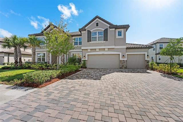 33255 Kateland Dr, Wesley Chapel, FL 33545 - townhome / multi-family property featuring stone siding, decorative driveway, stucco siding, a tile roof, and an attached garage