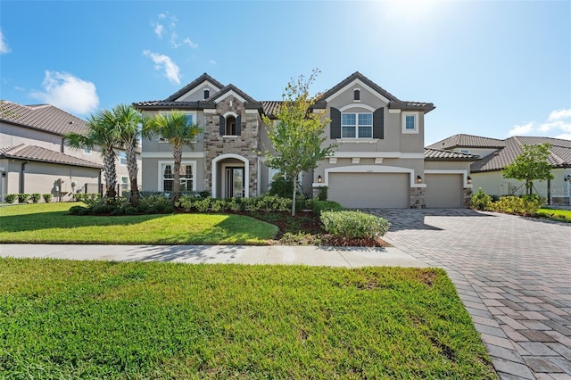 33255 Kateland Dr, Wesley Chapel, FL 33545 - view of front of house featuring stone siding, stucco siding, decorative driveway, a front yard, and a garage