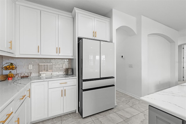 33255 Kateland Dr, Wesley Chapel, FL 33545 - kitchen with freestanding refrigerator, backsplash, white cabinetry, and light stone countertops