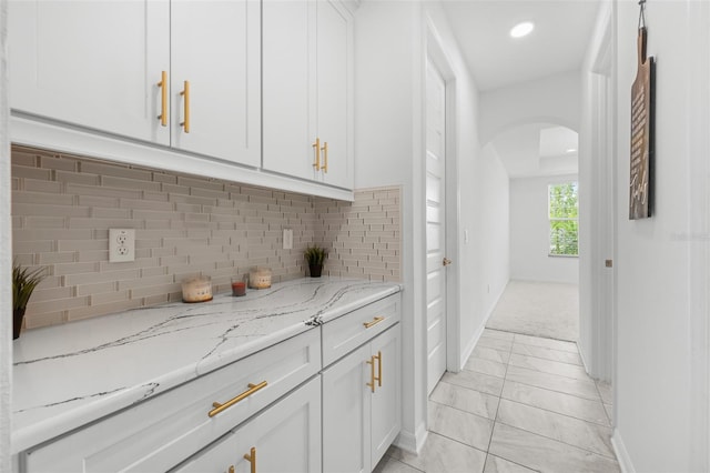 33255 Kateland Dr, Wesley Chapel, FL 33545 - kitchen with arched walkways, baseboards, light stone countertops, white cabinetry, and recessed lighting