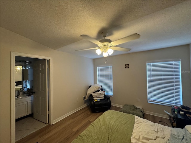 527 Glenn Cross Dr, Ruskin, FL 33570 - bedroom with wood finished floors, a textured ceiling, baseboards, a ceiling fan, and ensuite bath