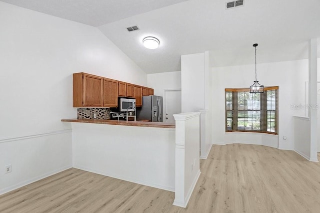 1017 Cameo Crest Ln, Valrico, FL 33596 - kitchen with appliances with stainless steel finishes, light wood-type flooring, brown cabinetry, hanging light fixtures, and high vaulted ceiling