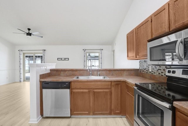 1017 Cameo Crest Ln, Valrico, FL 33596 - kitchen featuring stainless steel appliances, a sink, a peninsula, light wood-style flooring, and vaulted ceiling