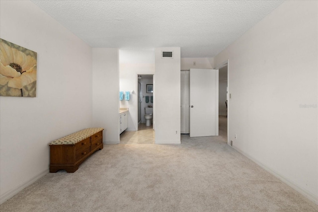 11485 Oakhurst Rd Unit 200-101, Largo, FL 33774 - bedroom with light colored carpet, connected bathroom, a textured ceiling, and baseboards