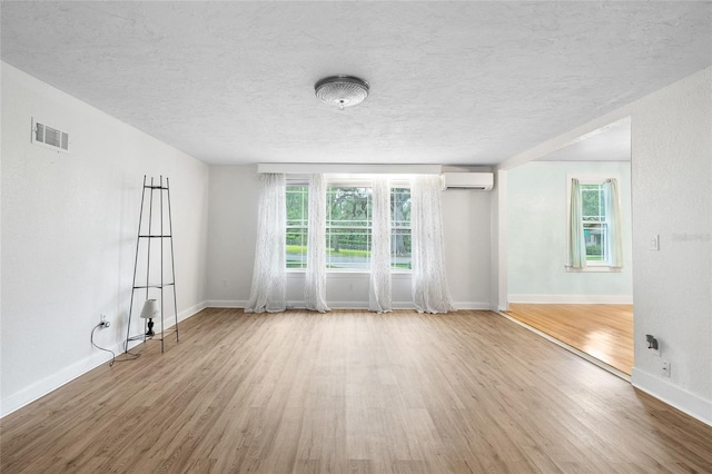 1226 SE 9th Ave, Ocala, FL 34471 - unfurnished room with a wall unit AC, wood finished floors, healthy amount of natural light, baseboards, and a textured ceiling
