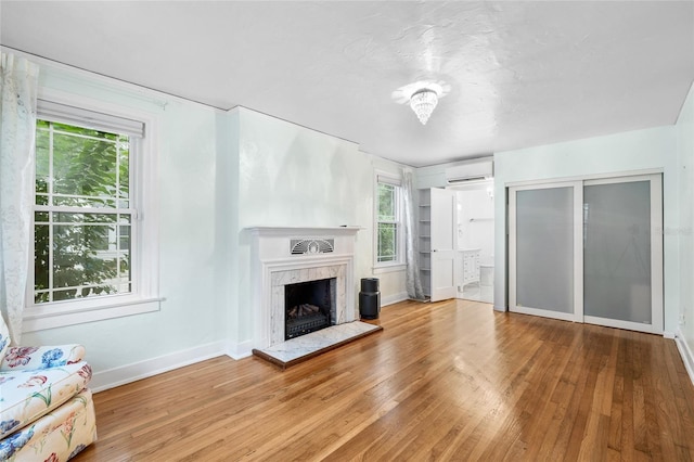 1226 SE 9th Ave, Ocala, FL 34471 - unfurnished living room featuring a wall mounted AC, wood finished floors, healthy amount of natural light, and a high end fireplace