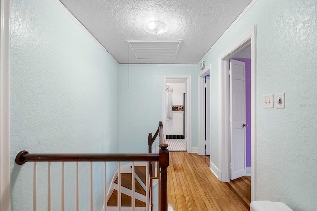 1226 SE 9th Ave, Ocala, FL 34471 - corridor with an upstairs landing, a textured wall, a textured ceiling, light wood-style flooring, and baseboards