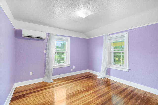 1226 SE 9th Ave, Ocala, FL 34471 - unfurnished room with a wall mounted air conditioner, a textured ceiling, wood finished floors, lofted ceiling, and baseboards