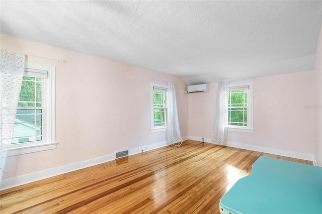 1226 SE 9th Ave, Ocala, FL 34471 - unfurnished room featuring an AC wall unit, wood finished floors, baseboards, and a textured ceiling