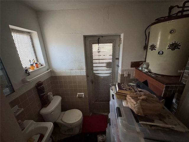 3730 NE 17th Ave, Pompano Beach, FL 33064 - bathroom featuring water heater, healthy amount of natural light, toilet, wainscoting, and tile walls