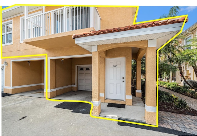 21007 Sunpoint Way Unit 203, Lutz, FL 33558 - view of exterior entry featuring a tile roof, stucco siding, and an attached garage