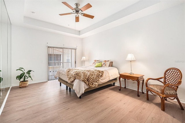 21007 Sunpoint Way Unit 203, Lutz, FL 33558 - bedroom featuring light wood-style floors, a tray ceiling, baseboards, access to outside, and ceiling fan