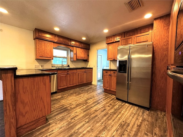 3419 Pearson Rd, Valrico, FL 33596 - kitchen featuring appliances with stainless steel finishes, a sink, dark wood-style floors, brown cabinetry, and dark countertops