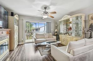 7523 Pitch Pine Cir Unit 184, Tampa, FL 33617 - living room featuring wood finished floors, ceiling fan, a glass covered fireplace, and baseboards
